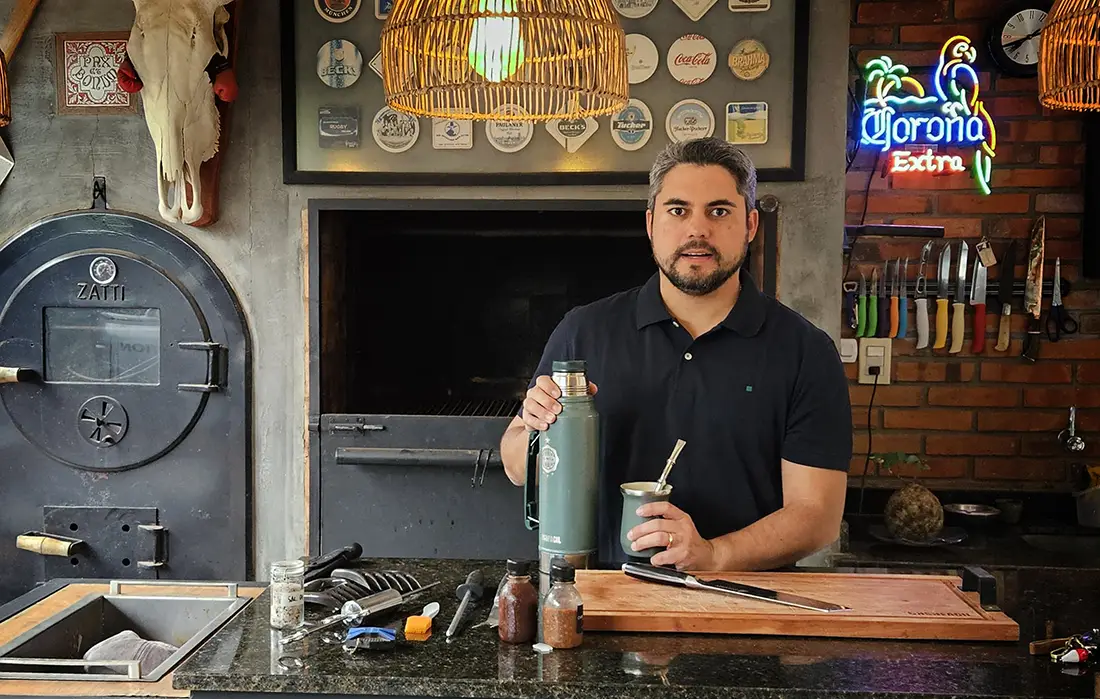 Miguel Guanes frente a la parrilla con fuego a leña, preparando cortes tradicionales en un entorno familiar.