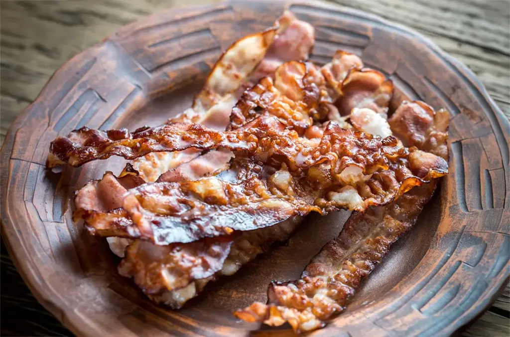 Panceta de cerdo con piel crocante terminada sobre brasas después de una cocción lenta.