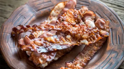Panceta de cerdo con piel crocante terminada sobre brasas después de una cocción lenta.