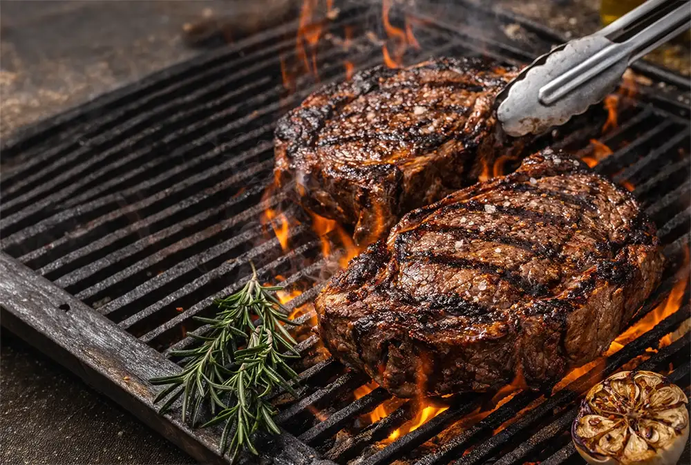 Medallones de ojo de bife sellándose sobre brasas intensas en una parrilla tradicional.